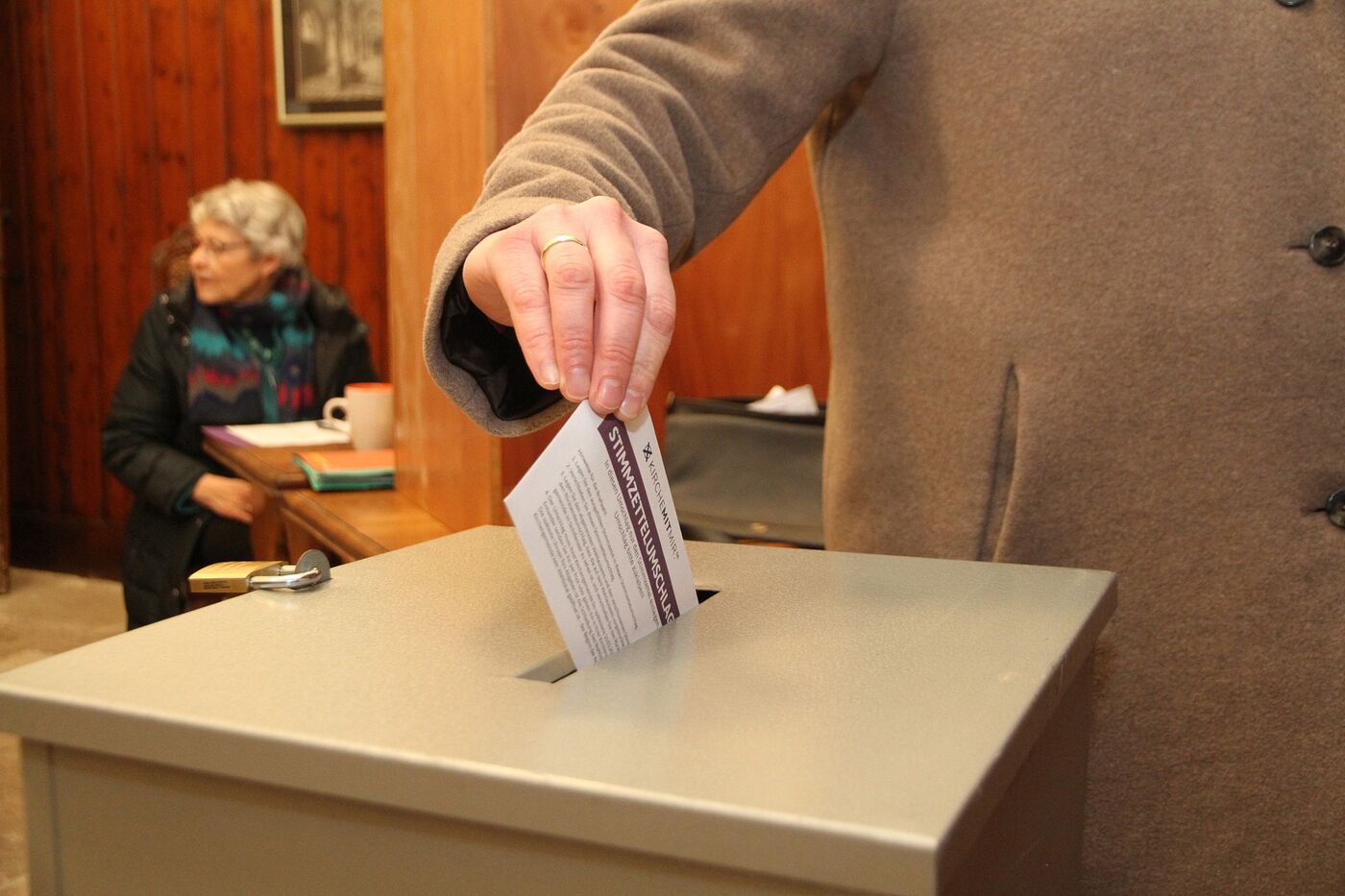 eine Frau im Wahllokal wirft ihren Stimmzettel in die Wahlurne.